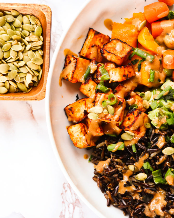 A hearty, protein filled bowl of goodness! This High Protein Mushroom Tofu Bowl is filled with wild rice, mushrooms, tofu, edamame beans, and topped with pumpkin seeds and a miso ginger dressing.